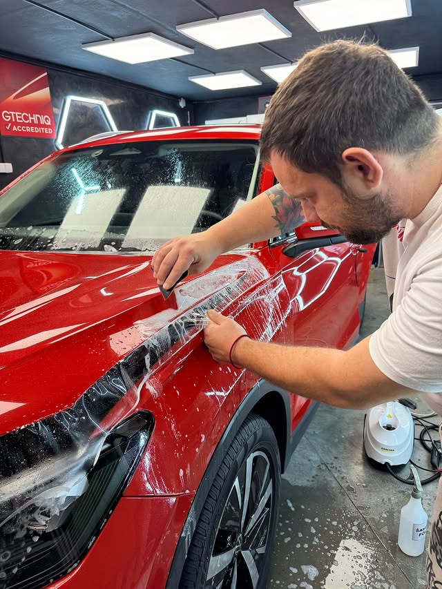 Peter počas aplikácie ochrannej PPF fólie na červený Volkswagen Tiguan